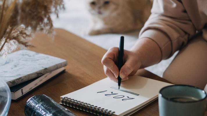 Person writing 2021 on a notepad