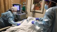 Clinicians in protective gear take care of an ICU patient. 