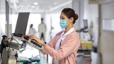 A nurse using a laptop to work on a medical report