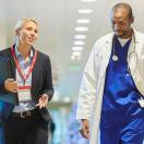 Doctor and healthcare worker talking in hospital hallway.