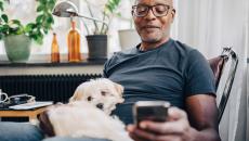 Man with his dog sitting at home having a mobile call with a care team member
