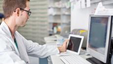 A clinician using a digital tablet and desktop computer