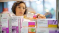 A pharmacist checking medicines on a rack