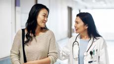 A doctor walking with a patient in a hospital corridor