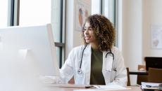 Doctor at a desktop computer looks at ease completing administrative burdens.