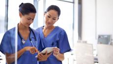 Nurses using a digital tablet to check a patient's medical record