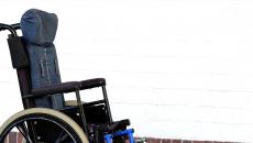A wheelchair, perhaps for an ALS patient, sits vacant by a wall.